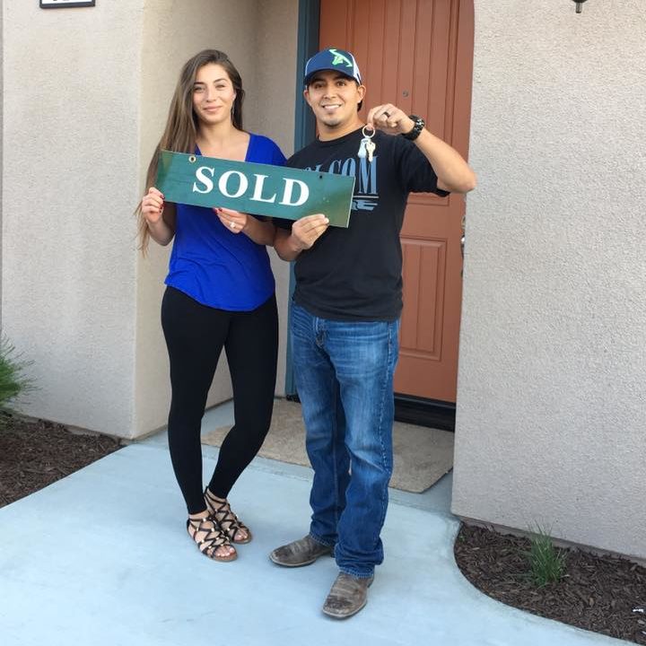 couple with sold sign at Pierce Real Estate in Hollister, CA.